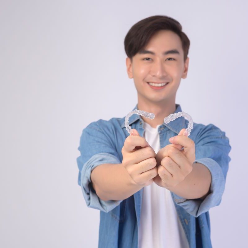 Young man holding Invisalign smiling in Camas, WA.