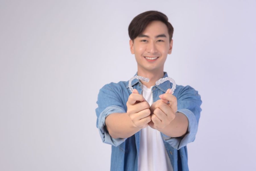 Young man holding Invisalign smiling in Camas, WA.